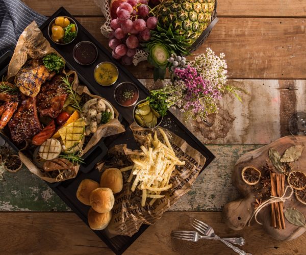 Plateau rempli de victuailles : frites, petits pains, fruits et autres légumes grillés au restaurant la Table de 3 à Bordeaux