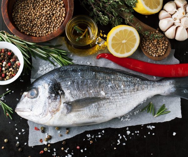 Poisson frais entier entouré d'épices et autres condiments dans les cuiines du restaurant la Table de Trois à Bordeaux